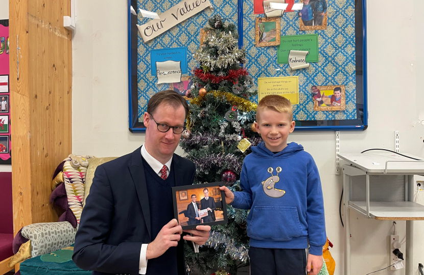 Tom Randall MP with Blake at Netherfield Primary School holding the running-up entry he designed alongside a framed photo of the Prime Minister with Blake’s design.